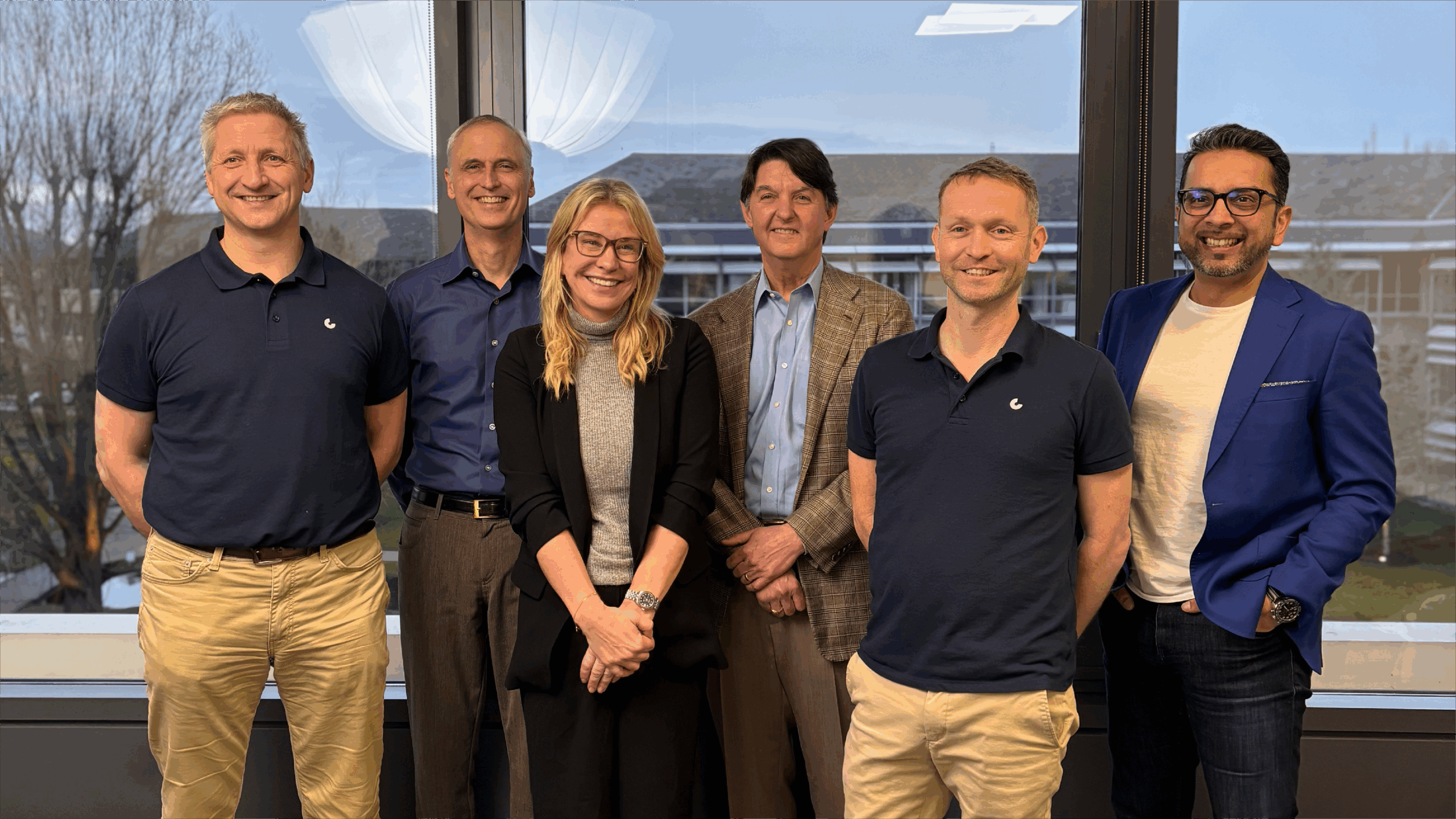 Group of six people smiling in office setting.
